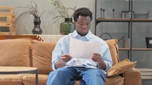 Adult Man Reviews Documents While Sitting on Couch