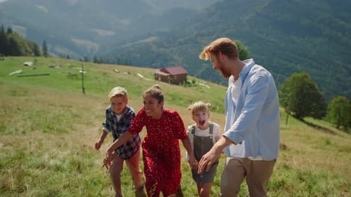 Playful Parents Have Fun with Children on Grassy Hill Sunny Day. Happy