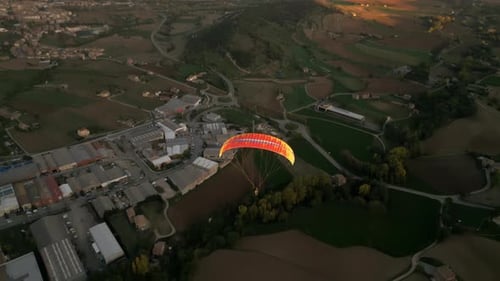 Aerial Shot Following a Paraglider Flying Above the Green Forest and Countryside