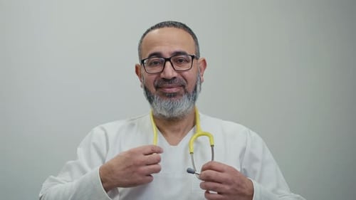 Friendly Doctor Puts on Stethoscope in Clinic