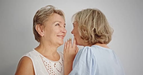 Two Women Whispering and Laughing Together Indoors