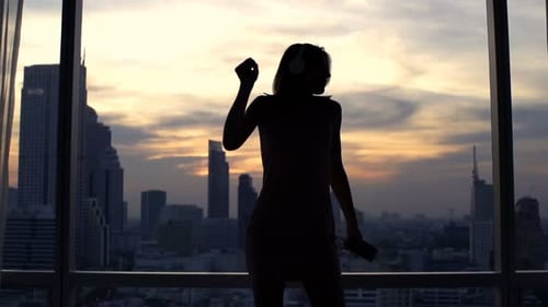Woman Listening to Music and Dancing near Window