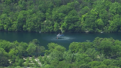 Feuerwehrhubschrauber schöpft Wasser aus dem See in den Eimer