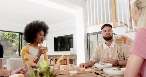 Friends toasting with drinks around dining table, enjoying meal together