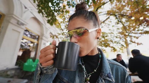 Cute Young Woman While Drinking Tea in Modern Street Cafe