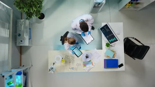 In a Shot From Above in a Lab of Two Scientists They are Both Discussing Their Work Checking Their