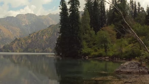 Foto de seguimiento, lago cristalino de Sary-Chelek rodeado de pintorescas montañas boscosas