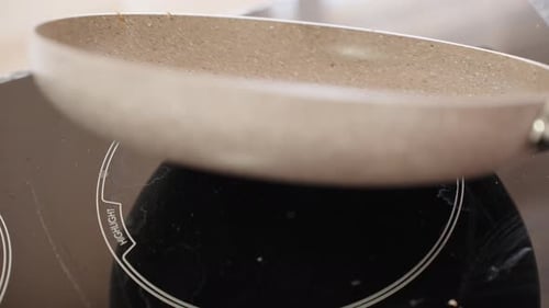 The girl pours pancake dough into a frying pan. Close-up.