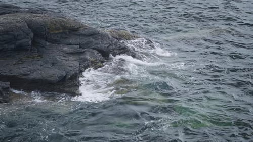 Waves Crashing on Rocky Shoreline on Overcast Day