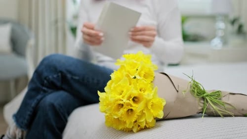 Woman Reads Letter with Bouquet of Flowers