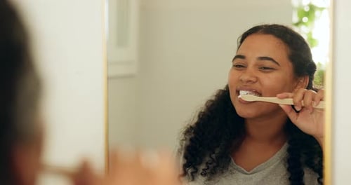 Woman Brushing Teeth in Mirror in Bright Bathroom