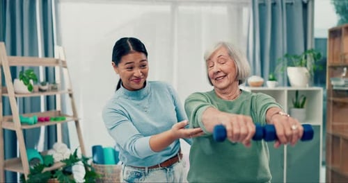 Woman Helping Senior Exercising With Weights at Home
