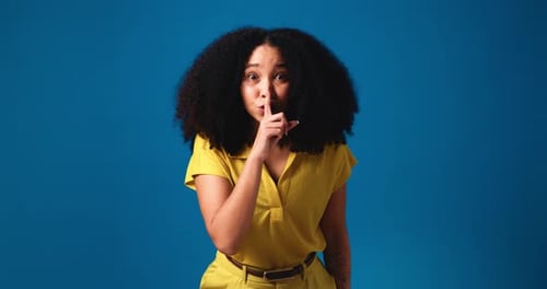 Secret, quiet and face of woman in studio with privacy, gossip or silence hand gesture