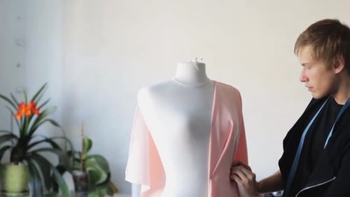 Fashion designer creates a new dress on a mannequin in a bright studio workshop