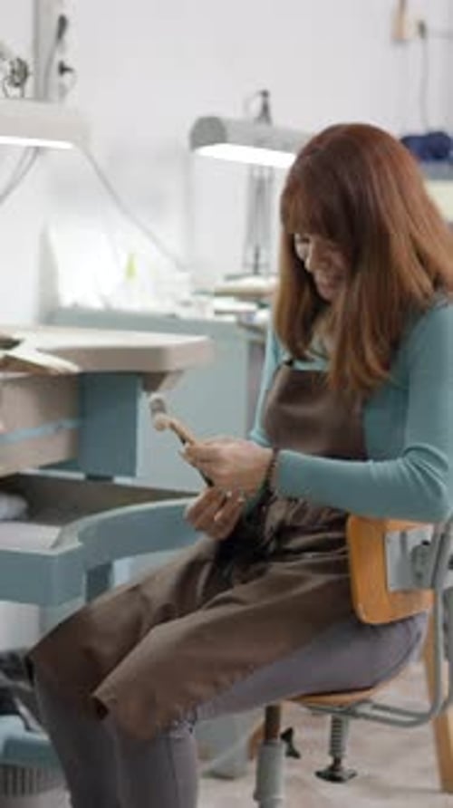 Woman Examining Jewelry Making Tools in Workshop