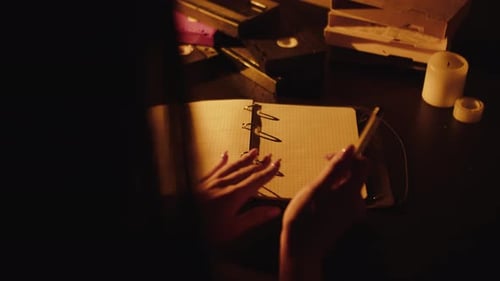 Woman Writes in Notebook by Candlelight