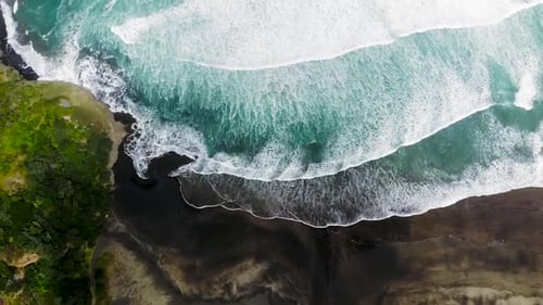 turquoise waves rolling onto black shore