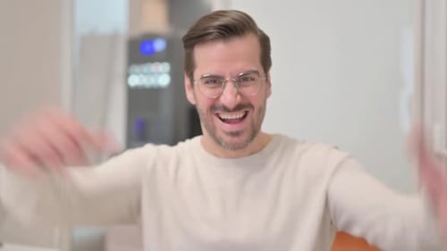 Young Man with Headset Doing Video Chat on Laptop in Call Center