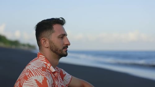 Serious Multiethnic Young Guy Sitting on the Ocean Background Thinking and Watching on the Ocean