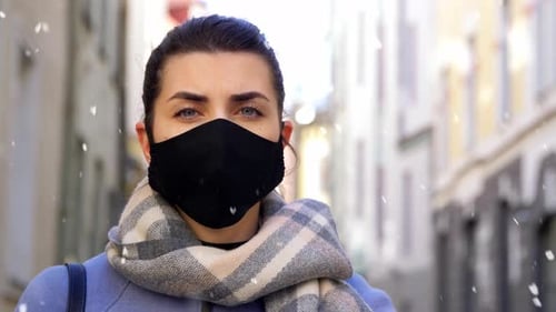 Woman in Mask During Winter Snowfall in City