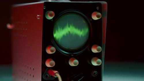 Osciloscópio iluminado em vermelho com forma de onda verde exibindo sinal analógico