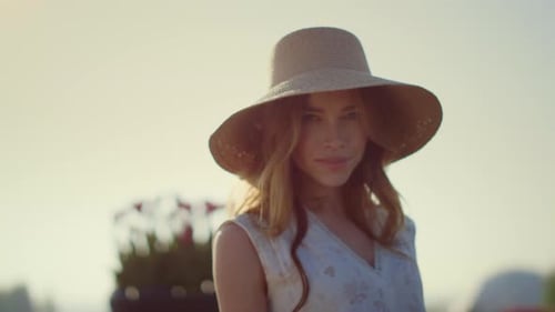Woman in sunhat looks at camera on sunny day