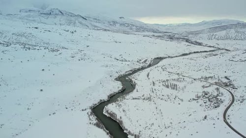 Aerial View of Snowy Winter Valley with River and Small Village