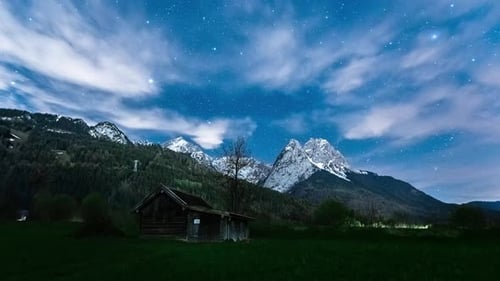 Timelapse Night Sky with fast-moving clouds over the Alps. Milky way stars rotating over the Alps