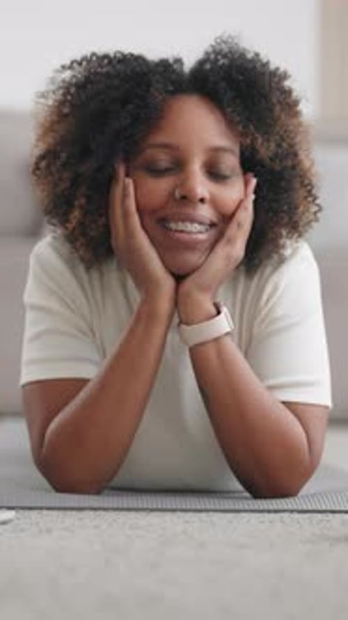 Smiling woman lying on mat in living room