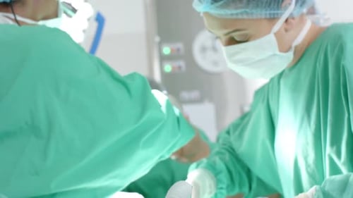 Verschiedene Chirurgen in OP-Kitteln operieren Patienten im Operationssaal, Zeitlupe