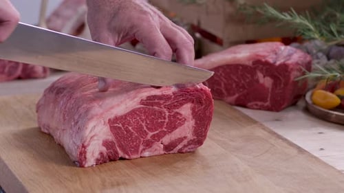 Chef Slicing Thick Raw Beef Roast on Wooden Board