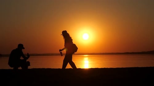 Silhouette of Young Family on the Beach at Sunset Dad Takes a Picture of His Kid