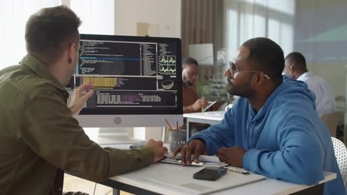 Experienced Programmer Showing Coding Script on PC to Male Newcomer at Office