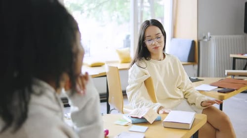 Dois estudantes multirraciais se envolveram em uma animada discussão enquanto estudavam em uma biblioteca moderna durante