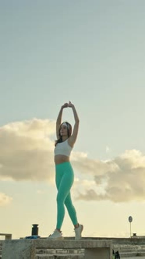 Woman stretching on a rooftop at golden hour