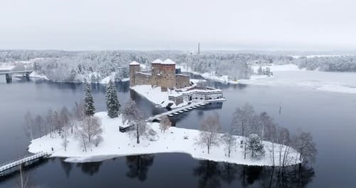 Aerial ascending shot of the snowy Olavinlinna castle in Savonlinna, Finland