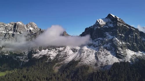 Majestic Snow Covered Mountain Peaks Piercing Through Soft White Clouds