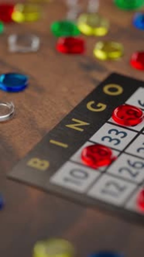 Vidéo verticale, plateau de bingo avec des jetons colorés sur une table en bois