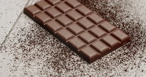 Delicious Milk Chocolate Bar On Powdered Cocoa with Wooden Background