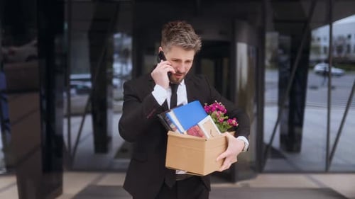 Man Stressed on Phone While Leaving Office After Job Termination