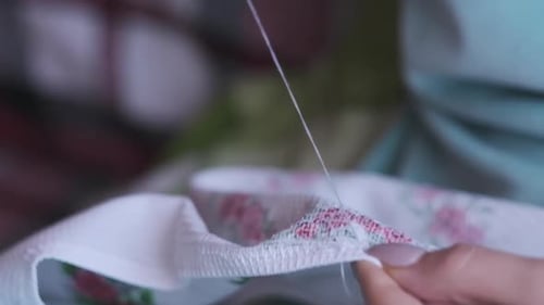 Adult Hands Skillfully Sewing Floral Fabric Close-Up