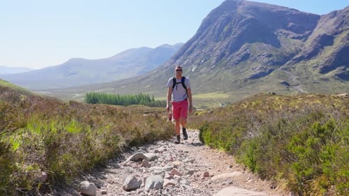 4K Front view of hiker walking in slow motion up steep trail in Scottish Highlands, United Kingdom