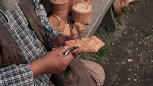 Russian master weaves baskets from wooden sticks. 4K close-up. Craft concept.