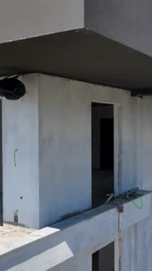 Vídeo vertical sobrevolando la perspectiva de un Zumbido de construcción costera sobre el trabajo junto al mar