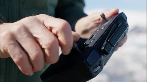 Man Operating Drone Controller in Snowy Mountain Setting