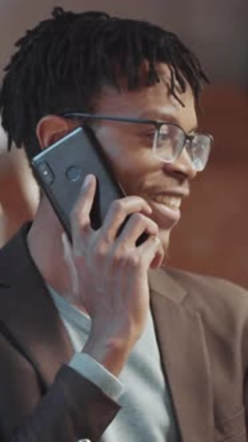 Vertical of Positive Black Male Entrepreneur Having Phone Conversation in Office