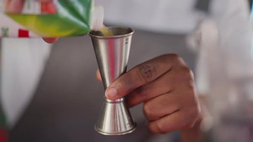 Barman Pours Juice Into Jigger in Bar