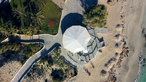 Aerial ascending shot of a gazebo by the beach.