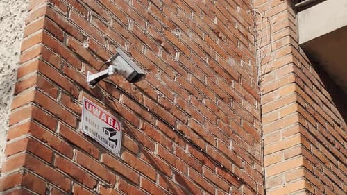 CCTV camera placed on the brick wall in front of the gate entrance to the residential estate.