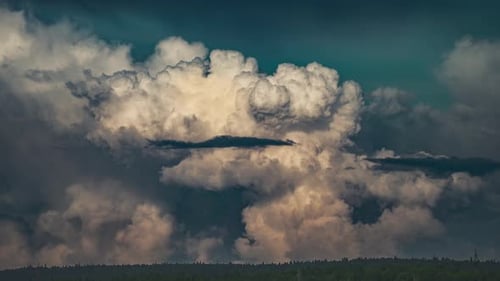 Massive Cumulonimbuswolken bilden sich und verwandeln sich vor einem leuchtend blaugrünen Hintergrund, der über ihnen schwebt